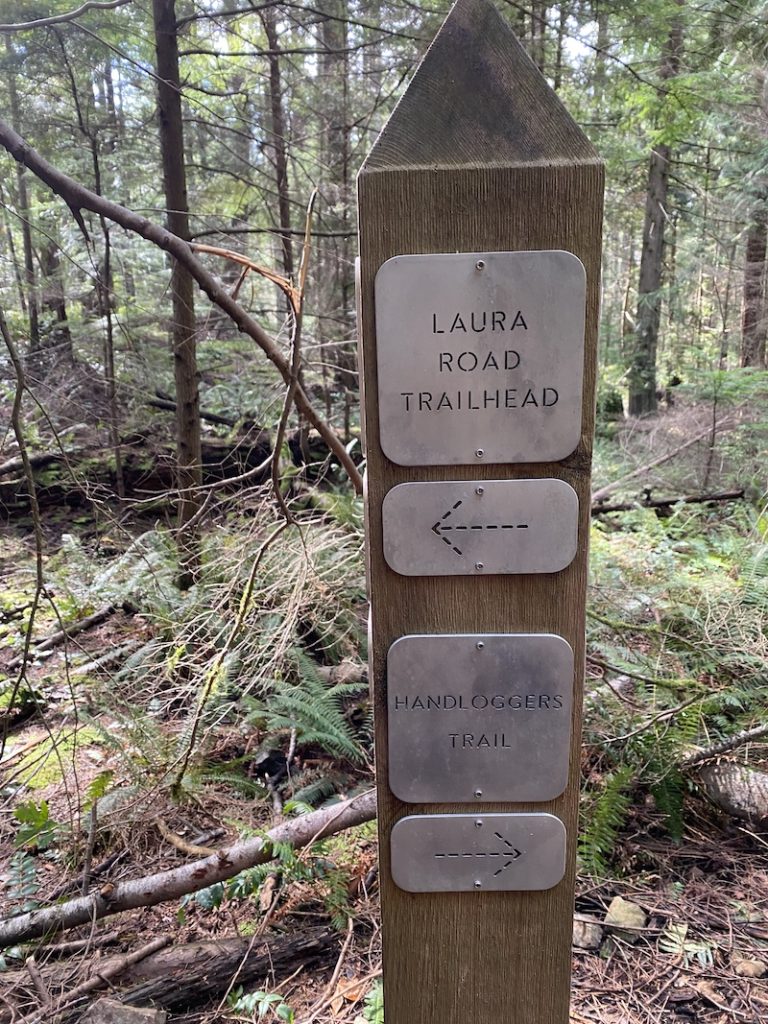 After hiking mount gardner and leaving, this signpost marks the way to Laura Road trailhead with a left arrow. Below that there is a Handloggers trail with a right arrow that hikers trying to leave should not follow.